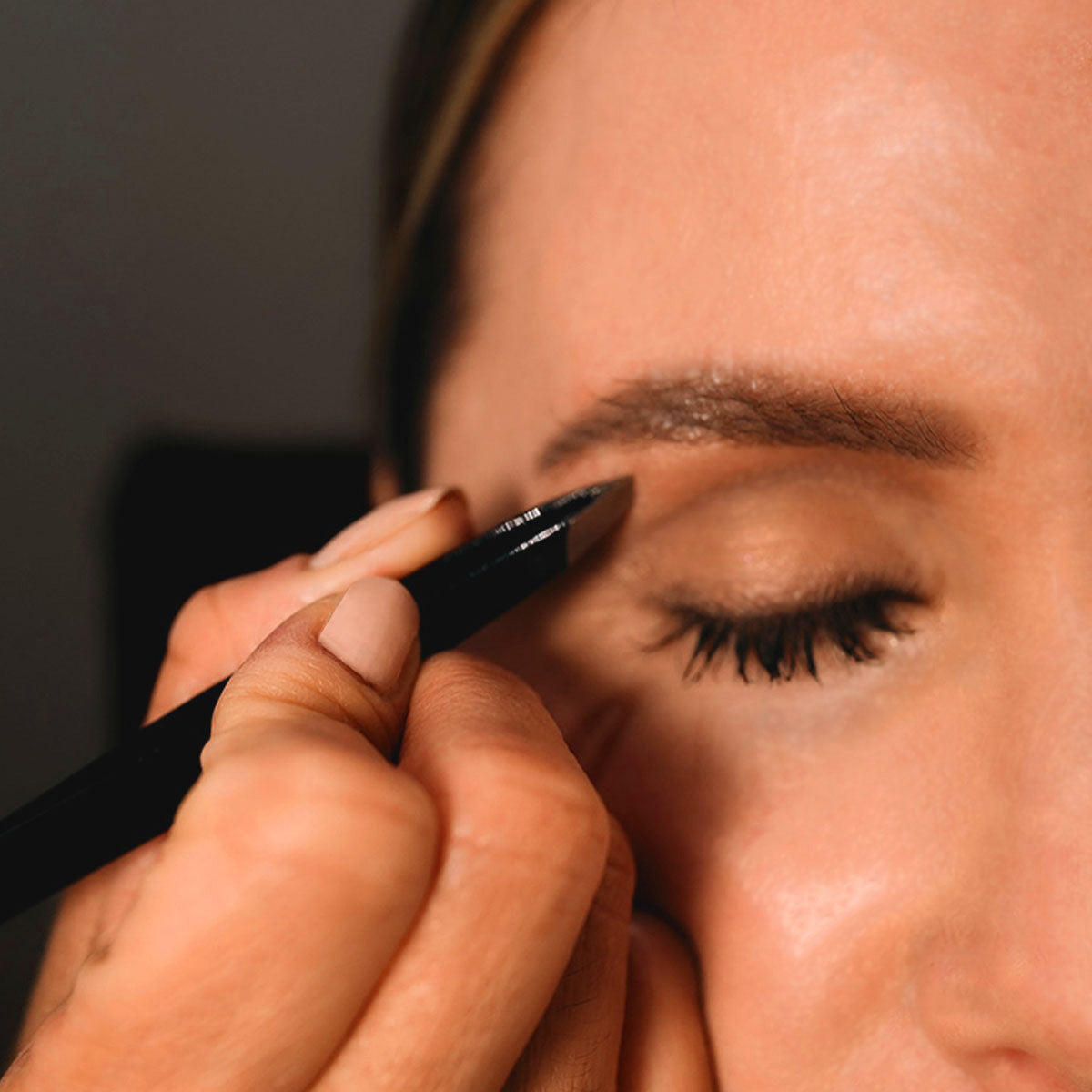Shaping an eyebrow with tweezers